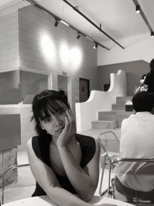 a black and white photo of a girl sitting at a table