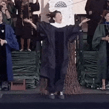 a woman in a graduation cap and gown is dancing on stage