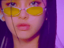 a close up of a woman wearing yellow sunglasses and a ring