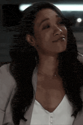 a close up of a woman wearing a white top and a gray jacket .