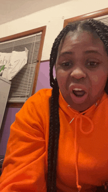 a woman wearing an orange hoodie is making a face