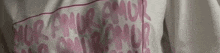 a close up of a person wearing a white shirt with pink letters on it .