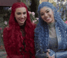 two women with long red hair and blue hair are standing next to each other and smiling .