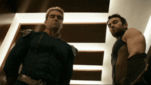 two men are standing next to each other in a room