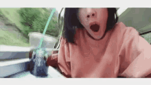 a woman is holding a starbucks cup with a straw in her mouth .