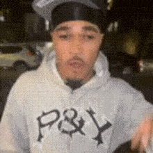 a man wearing a hat and a hoodie is standing on a street .