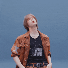 a person wearing a brown jacket and a black shirt with the letter r on it