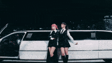 two women standing next to a white limousine with the door open