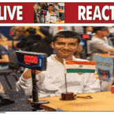 a man sitting at a table holding a small flag and a timer that says 0000