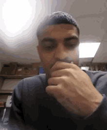 a man is covering his mouth with his hands in a dark room