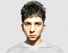 a young man wearing a white shirt looks at the camera with a serious look on his face