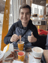 a young man is sitting at a table with a mcdonald 's cup