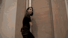 a woman in a black shirt is standing next to a wooden door