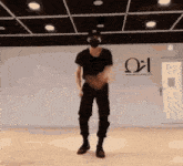 a man wearing a mask is dancing in a room with a greek letter on the wall .