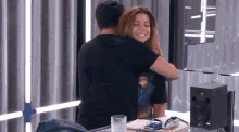 a man in a black shirt is hugging a woman