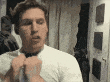 a man in a white shirt is adjusting his bow tie