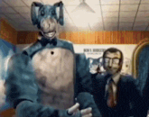 a man in a suit and tie is standing next to a man in a blue elephant costume