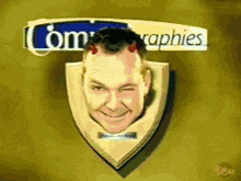a picture of a man 's head on a shield with com graphies written on the bottom