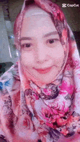 a woman wearing a hijab and a scarf is smiling for the camera .