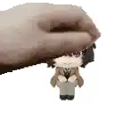a hand is holding a small figurine of a boy in a suit .