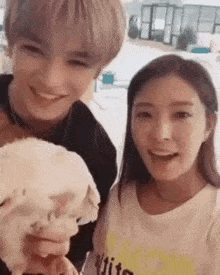 a man and a woman are posing for a picture while holding a dog .