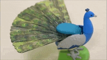 a peacock figurine with its tail spread is sitting on a table .
