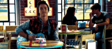 a man is sitting at a table playing a guitar in a diner .