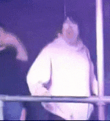 a blurry picture of a person in a white sweater standing in a dark room .