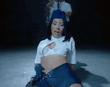 a woman in a blue hat and white top is kneeling down