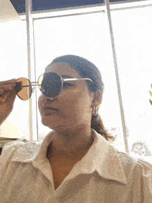 a woman in a white shirt is wearing sunglasses on her face