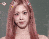 a woman with pink hair is making a face with her hands on her face .