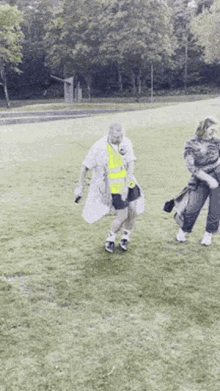 a man in a yellow vest is standing in a field