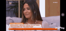 a woman is sitting on a couch in front of a tv screen that says tvi