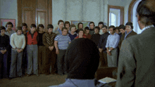 a group of men are standing in a circle with one man wearing headphones