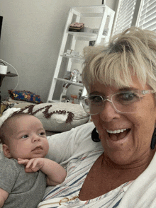 a woman wearing glasses holds a baby in her lap