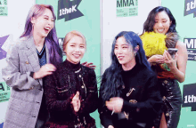 a group of women are posing for a picture in front of a sign that says mma