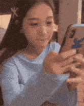 a girl in a blue shirt is looking at her cell phone