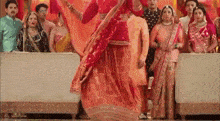 a group of people are standing around a woman in a red dress .