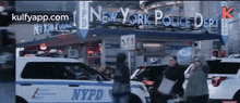 a group of people are walking in front of a new york police department