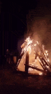 a large bonfire is burning in the dark in a field .