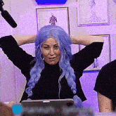 a woman with blue hair is sitting in front of a microphone .