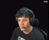 a man wearing headphones is holding a gun in front of a black background