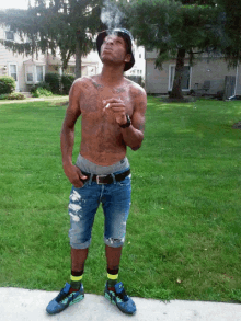 a shirtless man is smoking a cigarette while wearing a hat