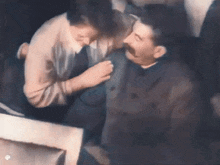 a man with a mustache is being kissed by a woman .