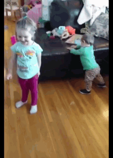 a little girl in a blue shirt is standing next to a little boy in a green shirt .