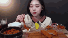 a woman is sitting at a table eating a variety of food with chopsticks