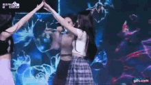 a group of women are dancing on a stage with their hands in the air