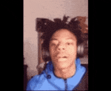 a man with dreadlocks is wearing a blue jacket and headphones .