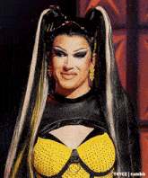 a drag queen wearing a black and yellow outfit and earrings
