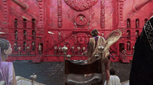 a group of people are standing in front of a large red wall